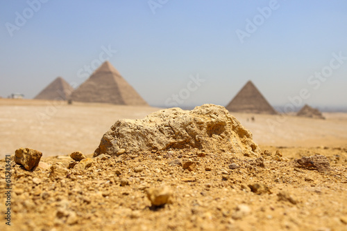 Emerging stone look like human face in egypt with pyramids on background
