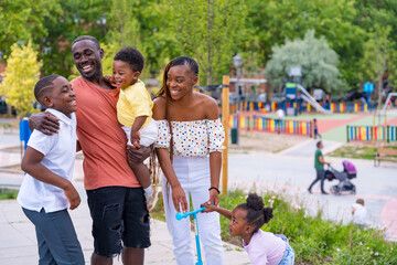 African black ethnicity family having fun with happy children together in playground, greeting each other after school
