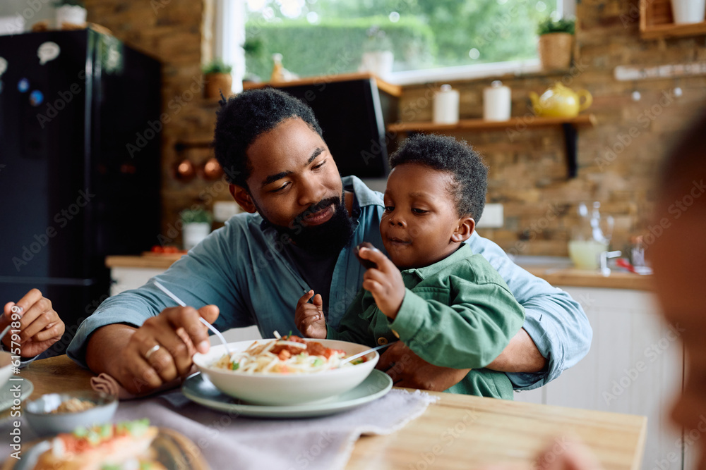 African American father and son enjoy in family lunch at dining table. African American father and son enjoy in family lunch at dining table.