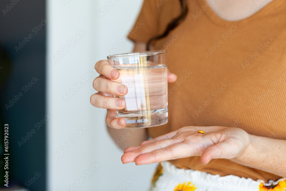 Woman with glass of water and orange medicinal tablet pill Woman with glass of water and orange medicinal tablet pill