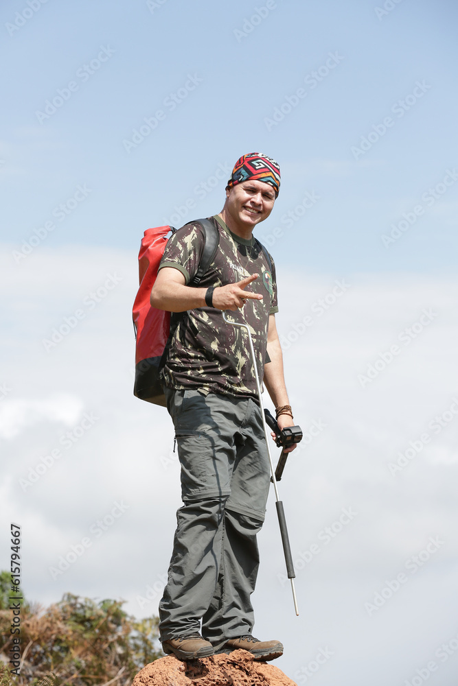 Caminhante homem com mochila caminhando no topo de uma montanha com fundo para paisagem.