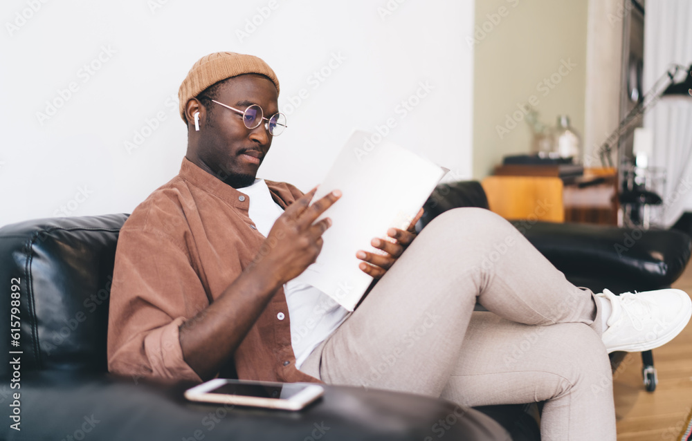 African American man sitting on sofa and reading book