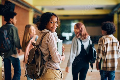 Foto Happy black teenage girl in high school hallway looking at camera
