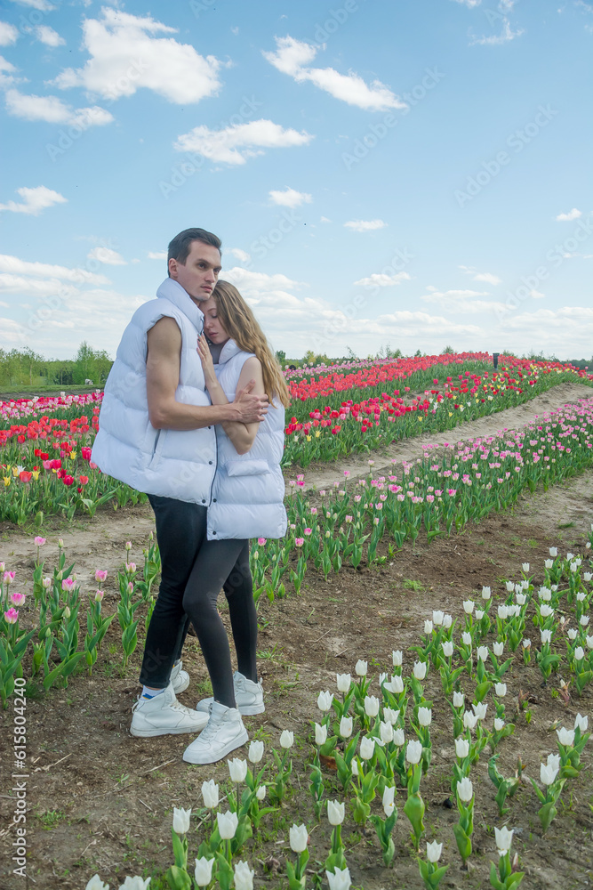 Guy and girl are hugs at field of colorful tulips.