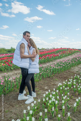 Obraz na płótnie Guy and girl are hugs at field of colorful tulips. w salonie