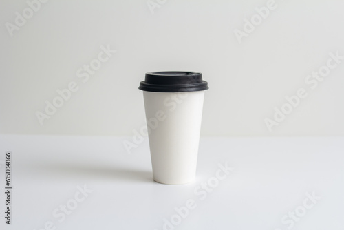 a white paper coffee cup with a lid without inscriptions stands on the table