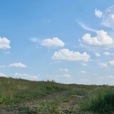 A grassy area with blue sky and clouds