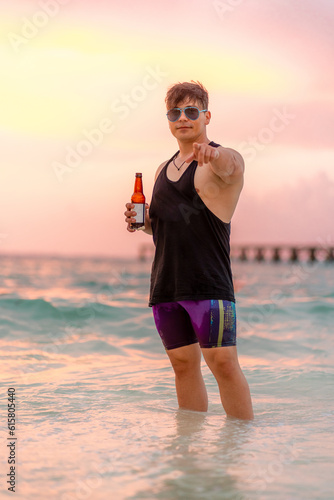 A handsome muscular man at the sea holding a bear. A beautiful caucasian man enjoying a sunny day at the beach in summertime.