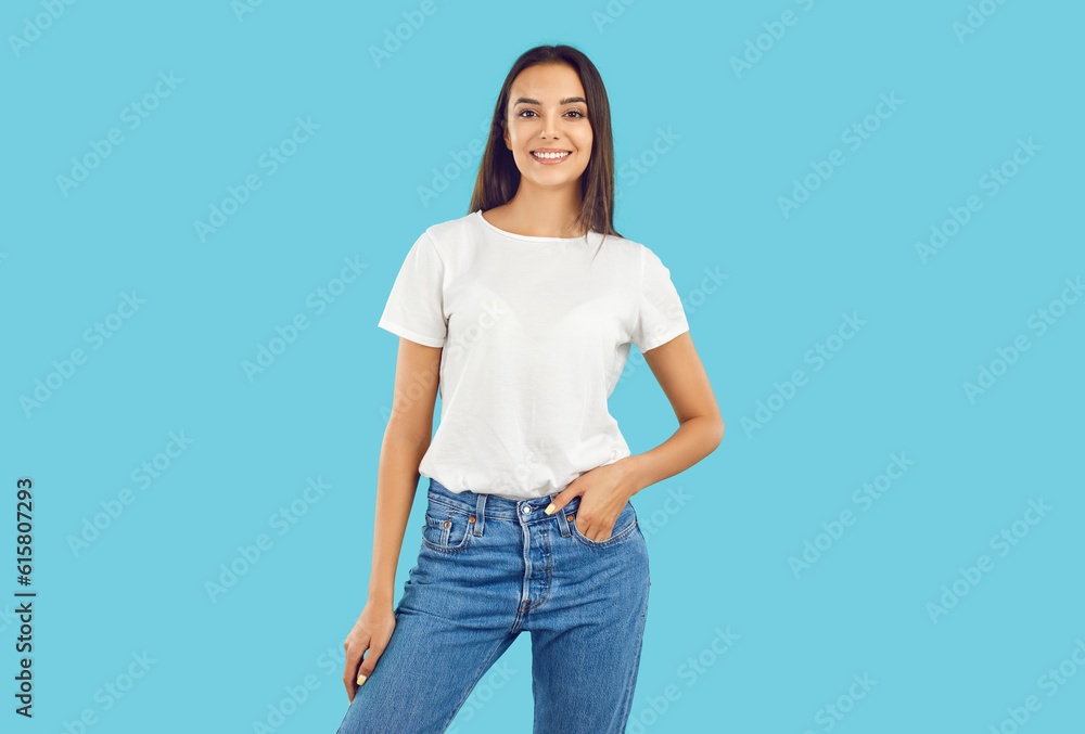 Studio shot of a young female model posing in casual clothes. Happy beautiful woman wearing a white mockup T shirt and comfortable blue jeans standing isolated on a blue background. Fashion concept Studio shot of a young female model posing in casual clothes. Happy beautiful woman wearing a white mockup T shirt and comfortable blue jeans standing isolated on a blue background. Fashion concept