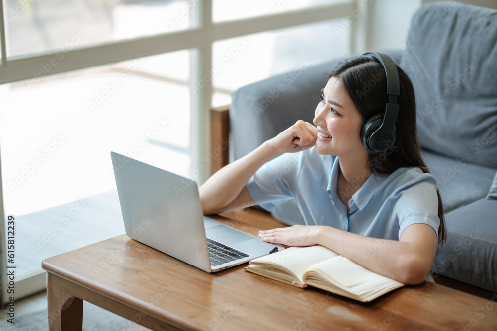 Beautiful asian woman online learning with laptop in living room.