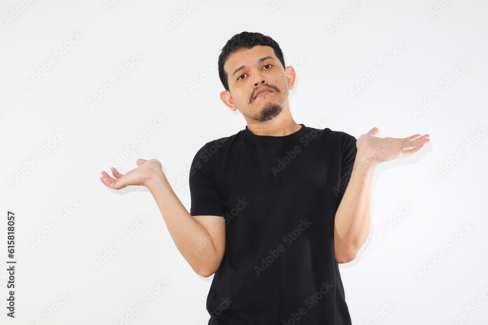 Young adult asian man raised arms and looking at camera with doubtful face. studio shot, isolated on light grey background. Young adult asian man raised arms and looking at camera with doubtful face. studio shot, isolated on light grey background.
