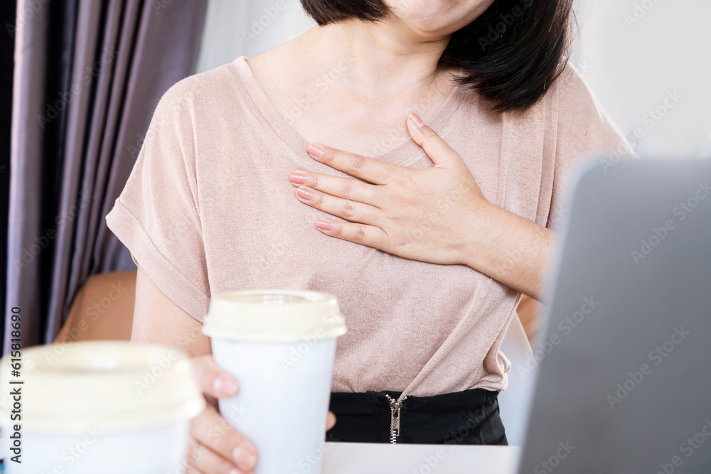 Asian woman having problems with heart palpitations or heart beating too fast after drinking coffee and too much caffeine - obrazy, fototapety, plakaty 