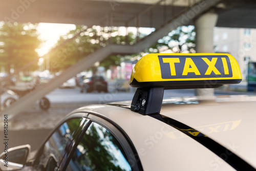 Foto Close-up detail yellow taxi symbol on cars roof stand waiting at parking of airport terminal or railway station against park warm evening bokeh sunlight