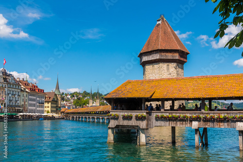 Lovely close-up view of the famous covered timber footbridge, the Kapellbrücke (Chapel Bridge), spanning the river Reuss diagonally in the city of Lucerne together with the Water Tower. 