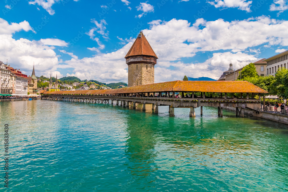 Picturesque view of Lucerne's landmark and symbol, the famous covered timber footbridge Kapellbrücke (Chapel Bridge) with the Water Tower, over the river Reuss with its turquoise water. Picturesque view of Lucerne's landmark and symbol, the famous covered timber footbridge Kapellbrücke (Chapel Bridge) with the Water Tower, over the river Reuss with its turquoise water.
