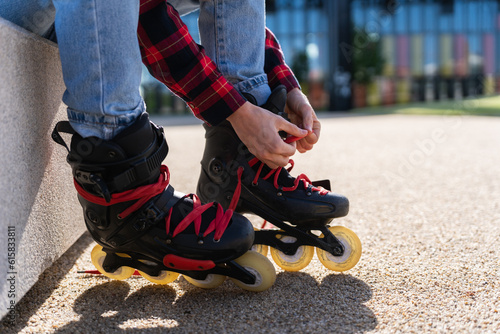 Young woman puts on roller skates in park on a sunny day. Closeup