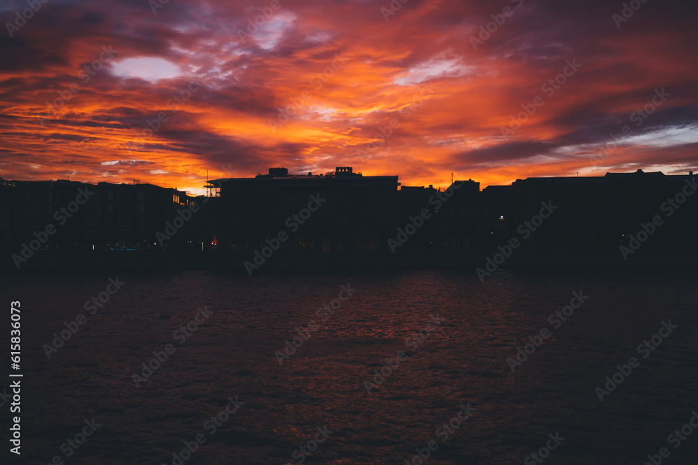 Bright sunset sky over silhouette of city and sea