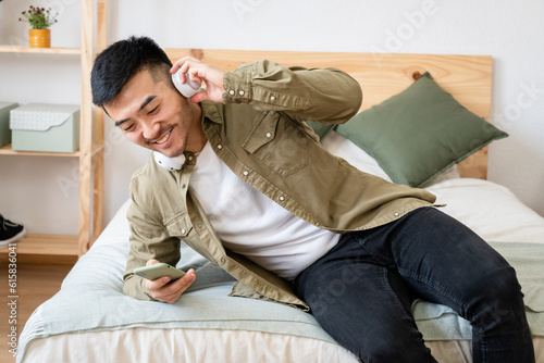 Man lying in bed watching videos on his cell phone.