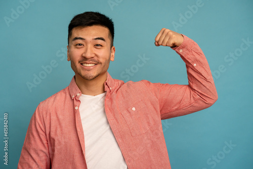 Smiling asian man flexing his arm.