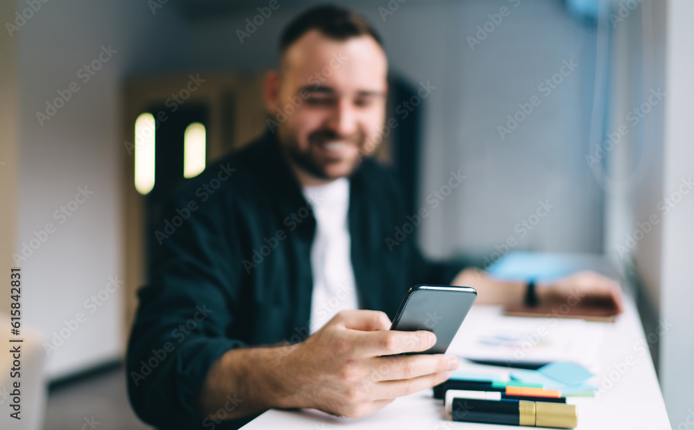 Soft focus of man browsing cellphone at table