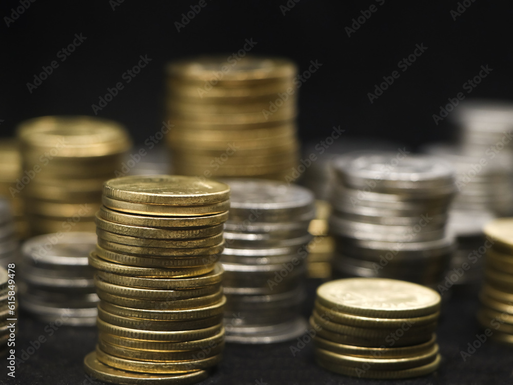 closeup shot of rows of gold and silver coins arranged and stacked in towers of different size isolated in a black background closeup shot of rows of gold and silver coins arranged and stacked in towers of different size isolated in a black background