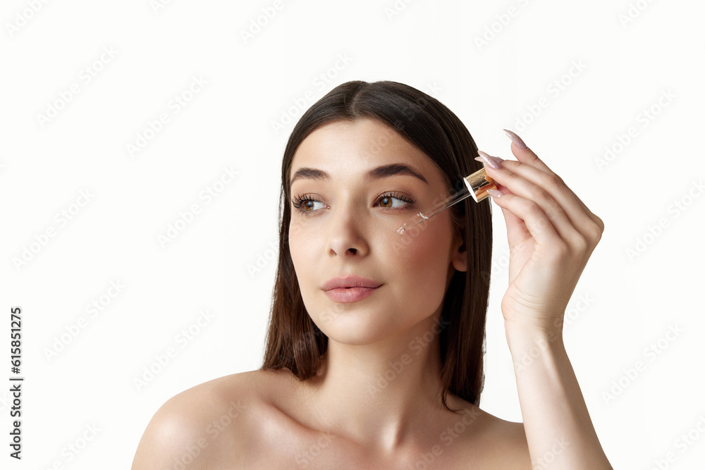 Beautiful, teder young woman taking care after skin with organic cosmetics, face serum, moisturizer over white studio background. Concept of female beauty, body and skincare, cosmetology, health, ad