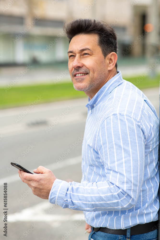 Mature man walking in the city with mobile phone Mature man walking in the city with mobile phone