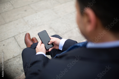 Businessman sitting on outside using mobile phone