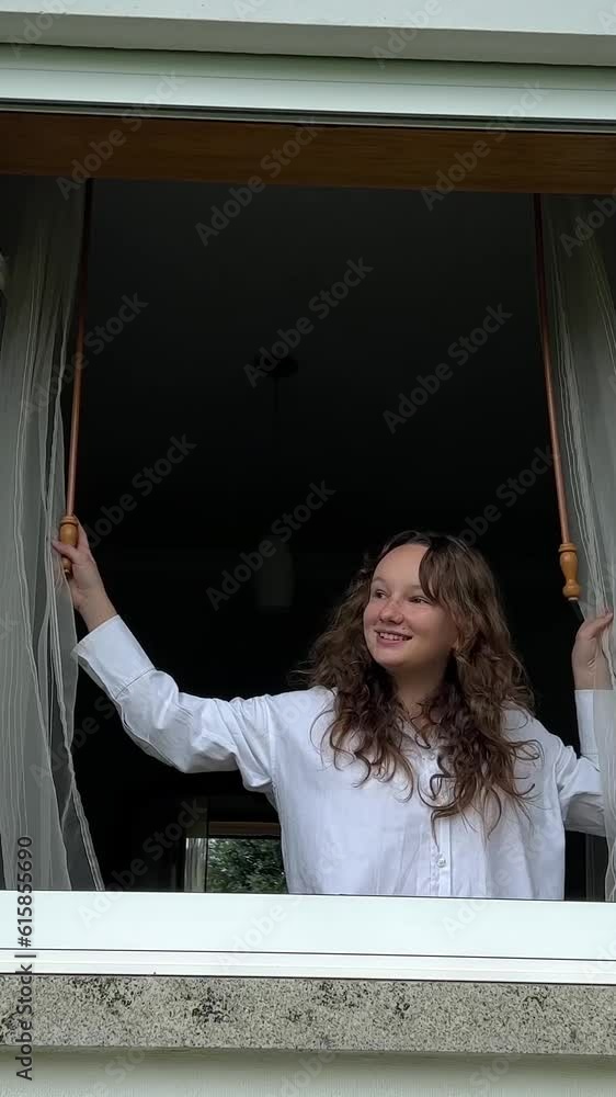 Window She a teenage girl splits the white curtains and looks out the white window ...
