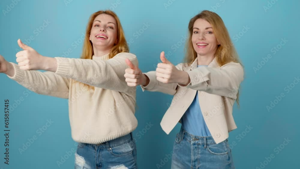 Friends, success and dancing woman celebration winning, excited. Two women sister having fun enjoying dance, friendly smiling for freedom, discount, sale or entertainment in studio on blue background Friends, success and dancing woman celebration winning, excited. Two women sister having fun enjoying dance, friendly smiling for freedom, discount, sale or entertainment in studio on blue background