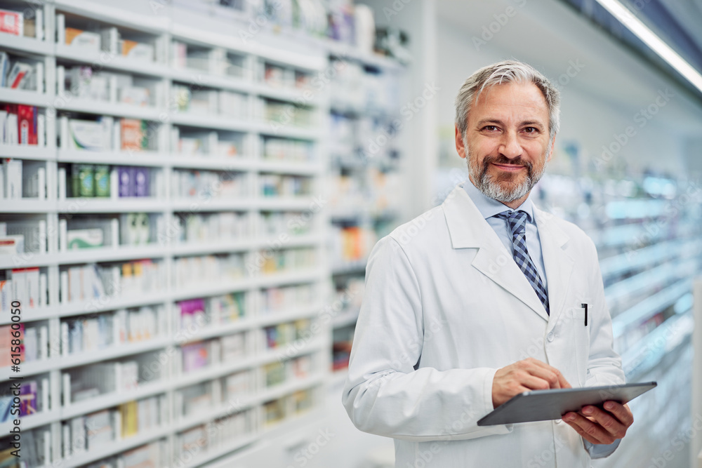 Portrait of a smiling senior male pharmacist holding a digital tablet.