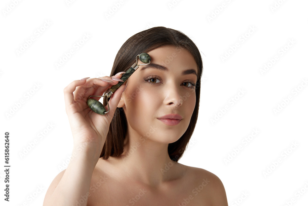 Beautiful young woman with well-kept healthy skin taking care after face with cosmetological massage roller over white studio background. Concept of female beauty, body and skincare, cosmetology, ad