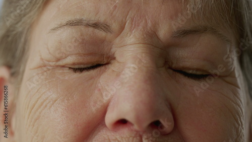 Senior woman closing eyes in contemplation in macro close-up. Eye_s detail of an older lady with wrinkles of wisdom in meditation. Person opening eyes and smiling