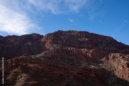 Panorama view of the brown rocky mountain peak and cliffs in the desert  under a blue sky.
