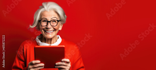 Happy Older Smiling Woman Holding a Tablet on a Red Banner with Space for Copy