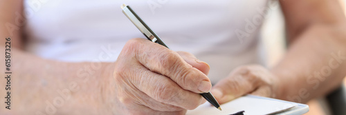 Old woman filling form with pen in clinic or in hospice