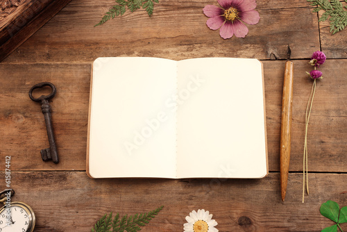 Top view of empty sketchbook, vintage objects and dry beautiful flowers over old wooden background. Copy space