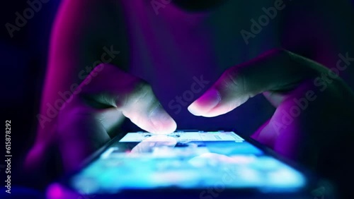 Finger of woman touching scroll page app on mobile phone.In a room with blue and purple neon tones.concept Social media and marketing