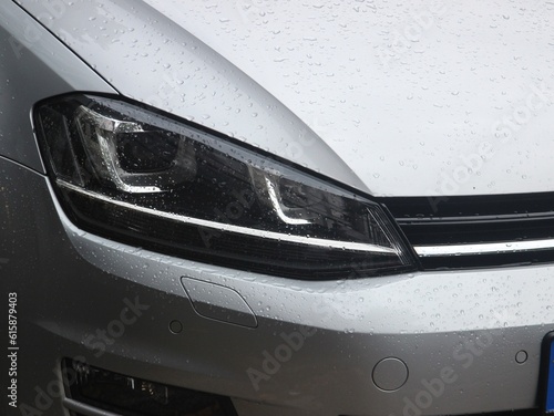 Silver crossover vehicle headlight in the rain. 