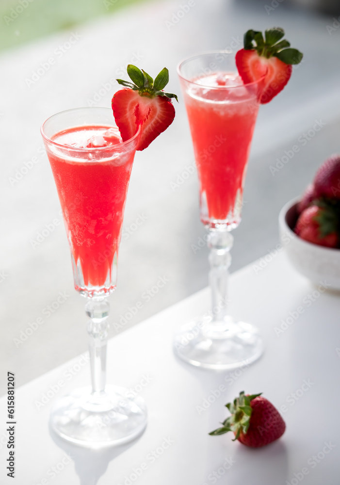 Refreshing strawberry Mimosas on a table against a sunny window. Refreshing strawberry Mimosas on a table against a sunny window.