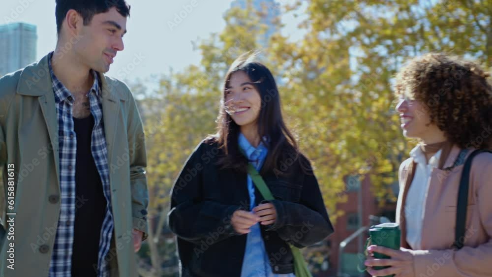 Young joyous man greeting female friends with hugs, smiling and chatting with them when meeting for a walk after working day in the city Young joyous man greeting female friends with hugs, smiling and chatting with them when meeting for a walk after working day in the city