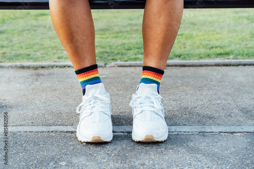 Close up LGBT persons legs wearing rainbow socks and white shoes on concrete ground. Loneliness, sadness for homosexual discrimination. Fight for equality, freedom, human rights. Pride month.