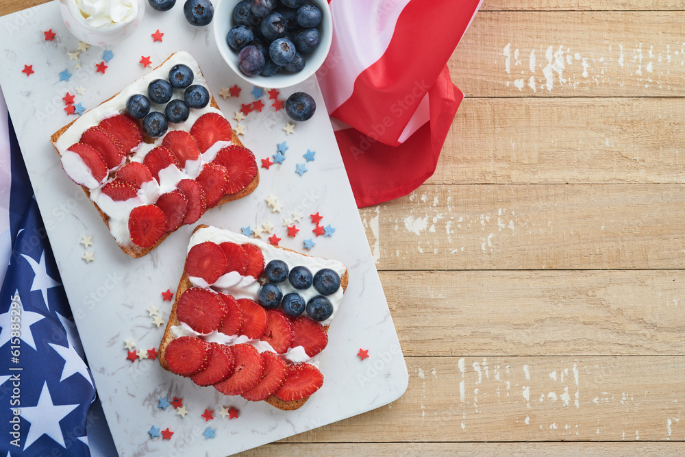 Obraz premium 4th of July American Independence Day food. American flag sandwich with strawberries, blueberries, whipped sweet cream, soft cheese on toast bread. Independence or Patriotic Day breakfast idea Mock up