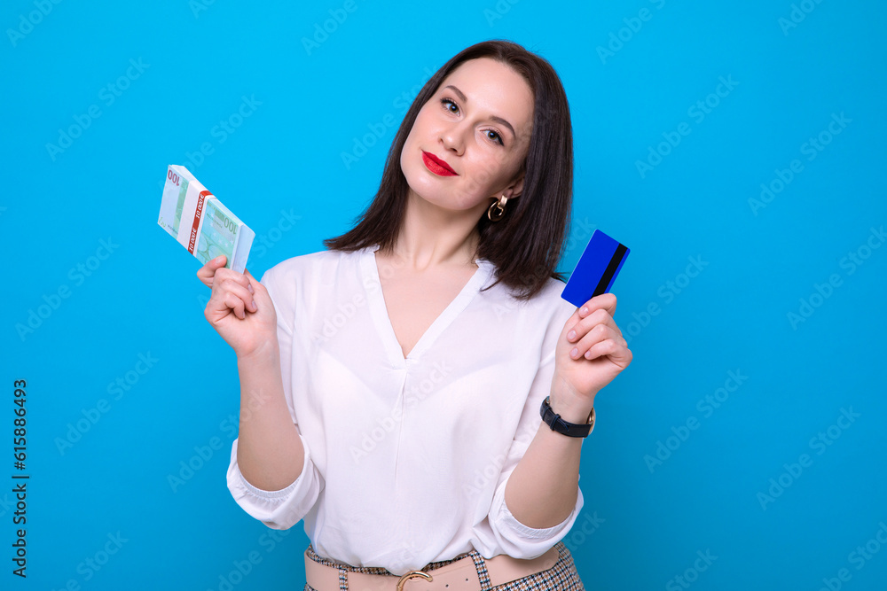 Portrait of a business woman with a wad of money and a bank card on a blue background.Economics and Finance Portrait of a business woman with a wad of money and a bank card on a blue background.Economics and Finance