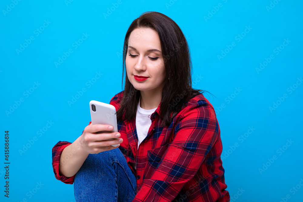 Young woman in red shirt with phone on blue background Young woman in red shirt with phone on blue background