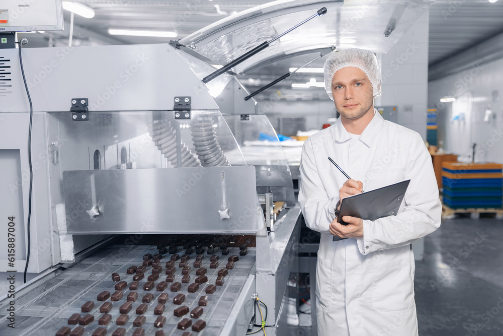 Chocolate factory worker inspecting production line conveyor with