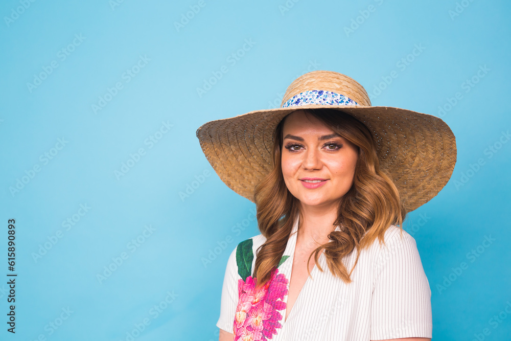 Holidays, summer, fashion and people concept - Girl in fashionable clothes straw hat. Portrait of charming woman on blue background with empty copy space.