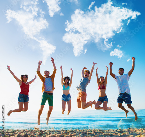 Happy smiling friends jumping over the sea of the beach over a blue sky with a world map made of clouds