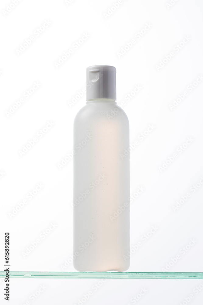 A bottle of cosmetics with a place for your logo on a glass shelf. Skin care. A bottle of cosmetics with a place for your logo on a glass shelf. Skin care.