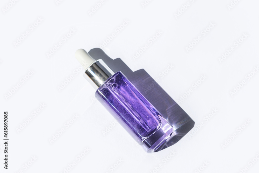 Purple cosmetic serum bottle with hard shadow on white background. Trendy selfcare products. Top view, flat lay Purple cosmetic serum bottle with hard shadow on white background. Trendy selfcare products. Top view, flat lay